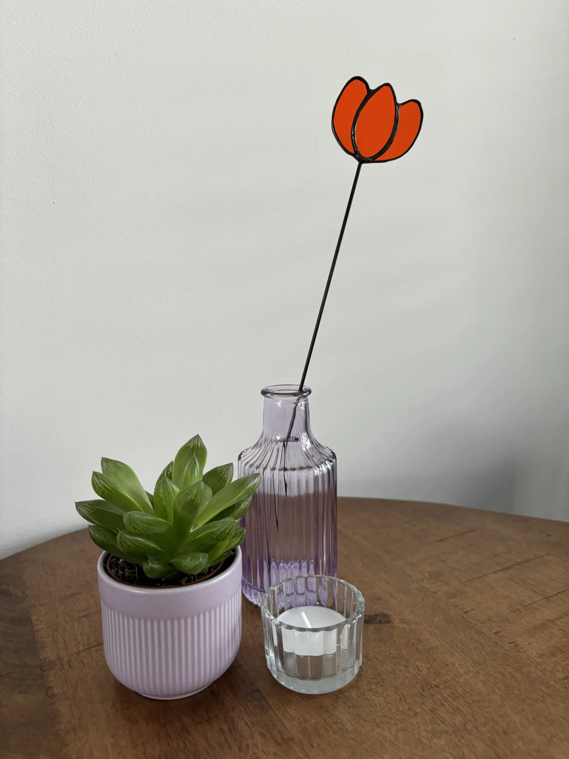 Tiffany glaskunst: oranje tulp op een steel in een vaasje.