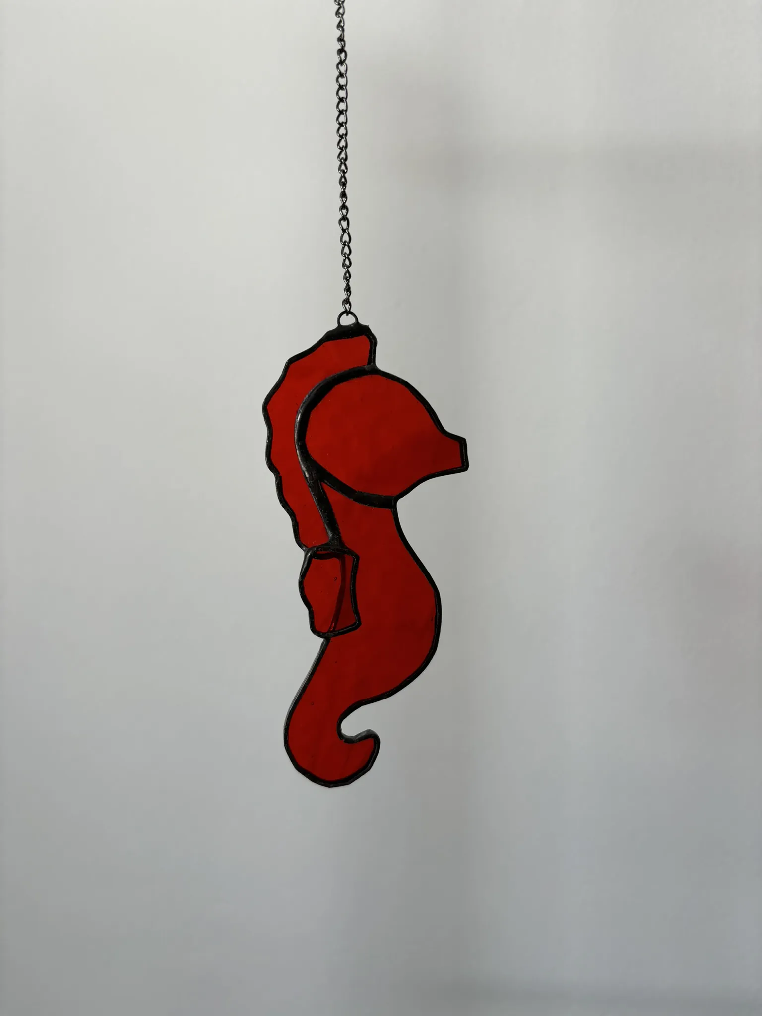 Glas in lood hanger: een rood zeepaardje.
