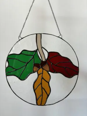 Glas in lood hanger: een hanger met daarin herfstblaadjes en eikels.