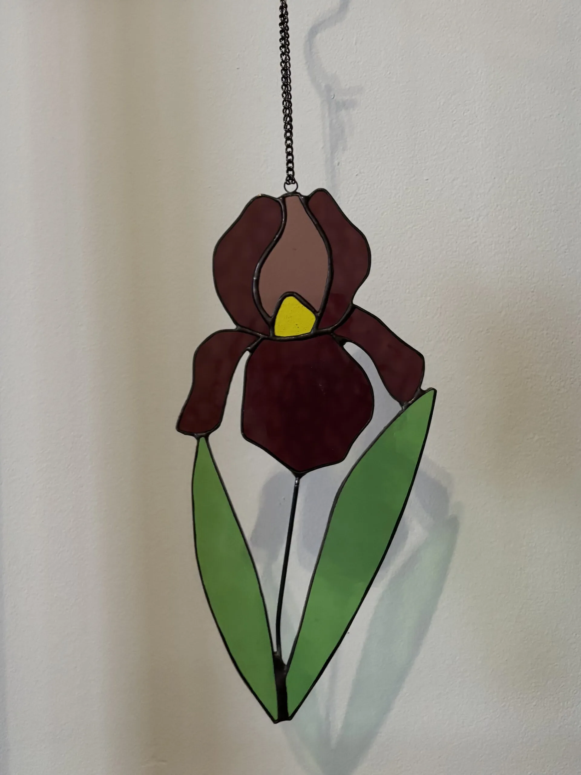 Glas in lood hanger: een iris in de kleur magenta met licht groene bladeren.