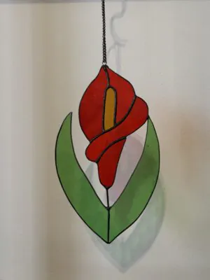 Glas in lood hanger: een rode lelie met licht groene bladeren.