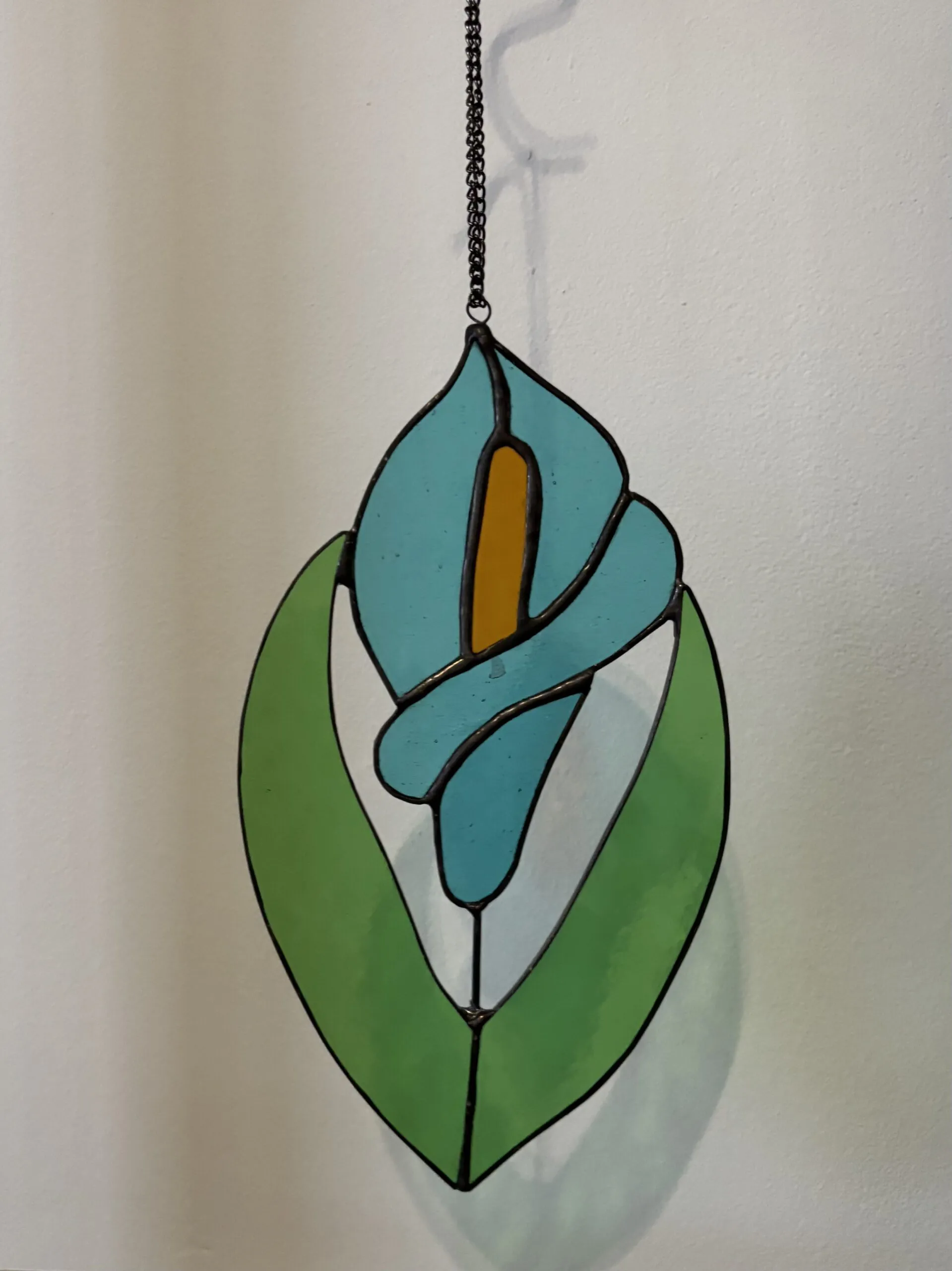 Glas in lood hanger: een blauwe lelie met licht groene bladeren.