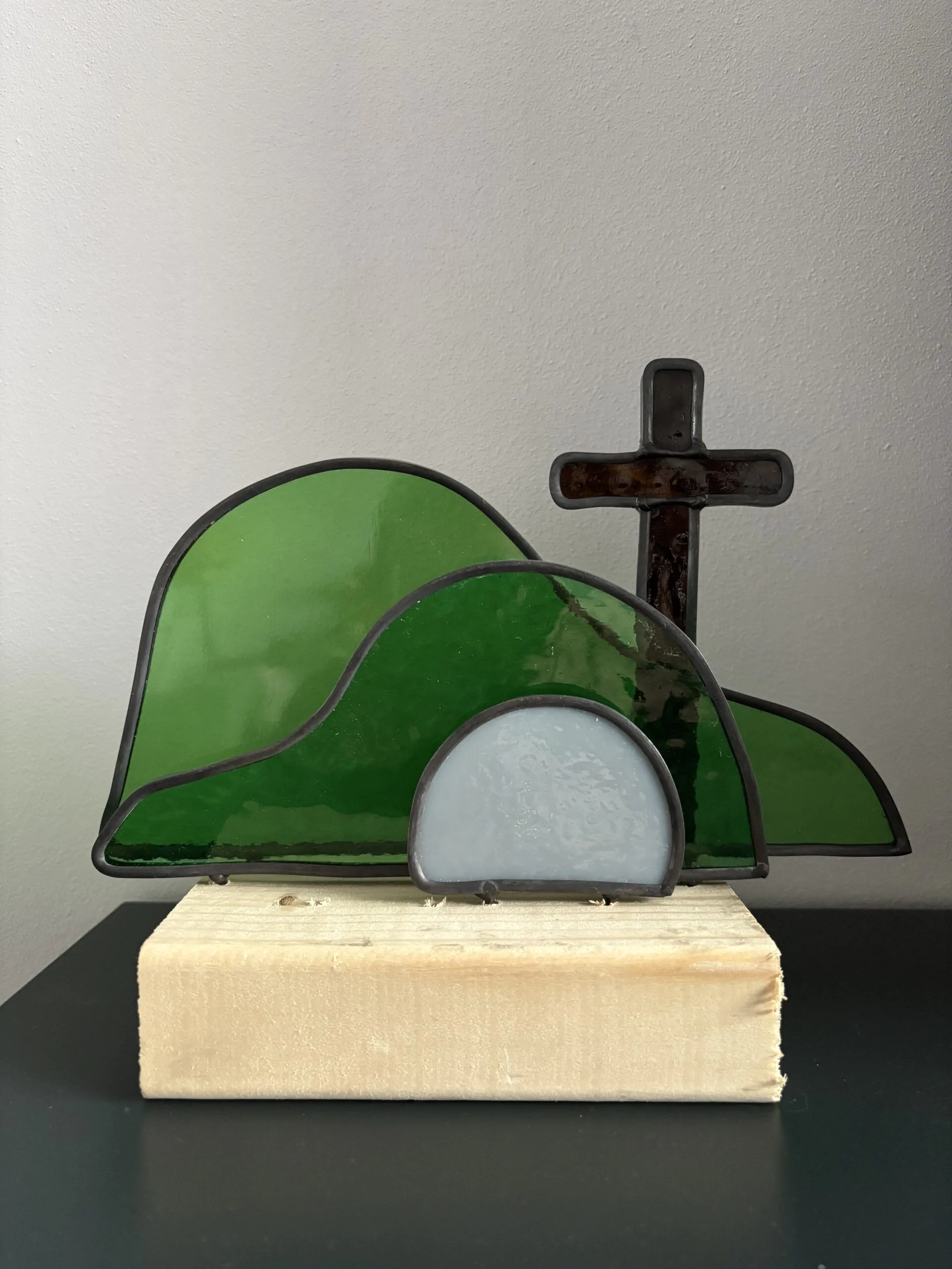 Glas in lood glaswerk: een Paasscène met het gesloten graf, de steen en het kruis.