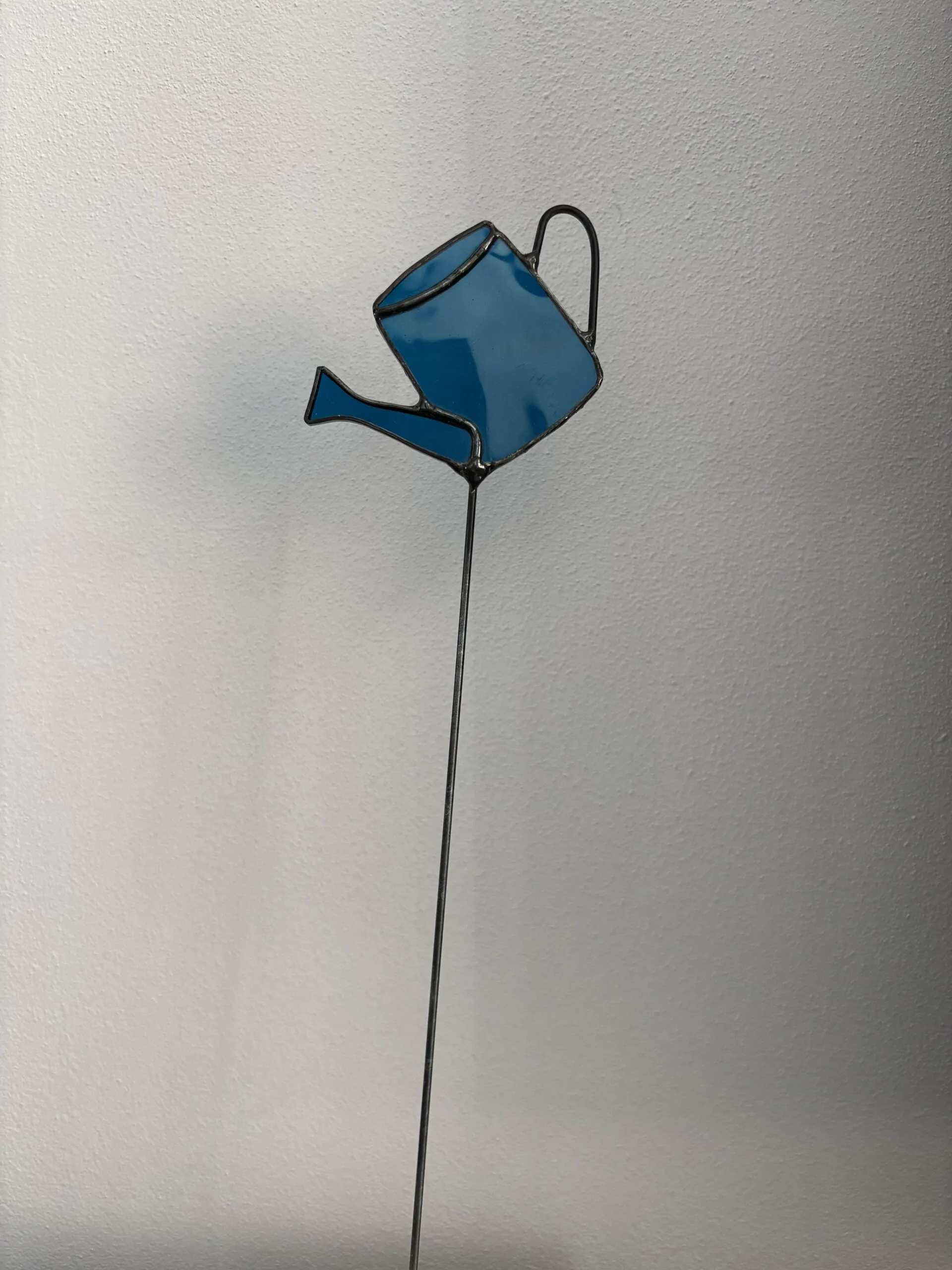 Tiffany glaskunst: een blauwe gieter op een steel.