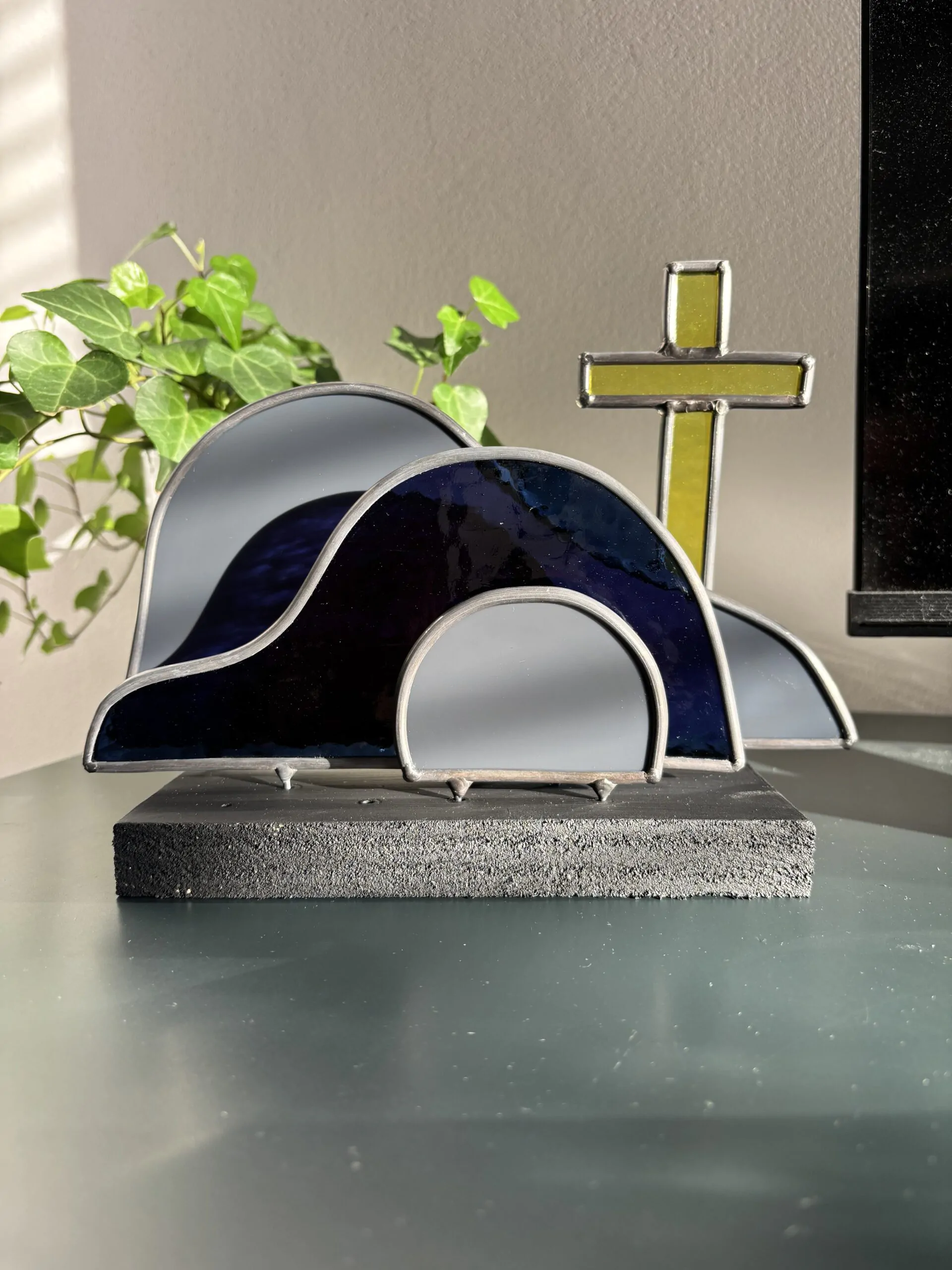 Glas in lood glaswerk: een Paasscène met het gesloten graf, de steen en het kruis.