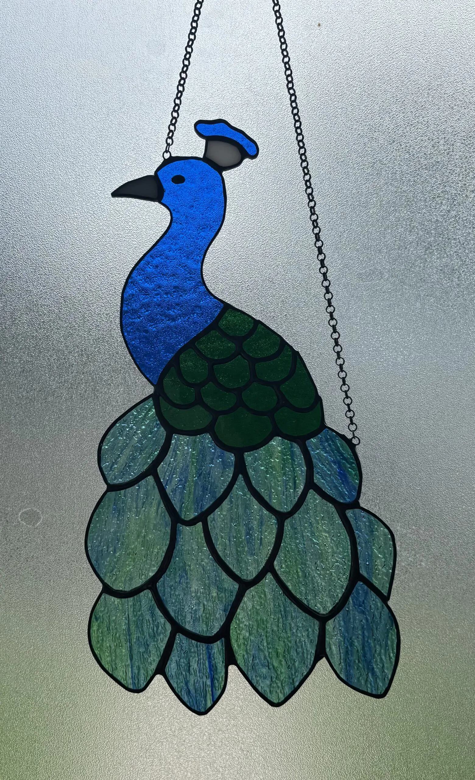 Glas in lood hanger: een pauw gemaakt met Tiffany en transparant glas.