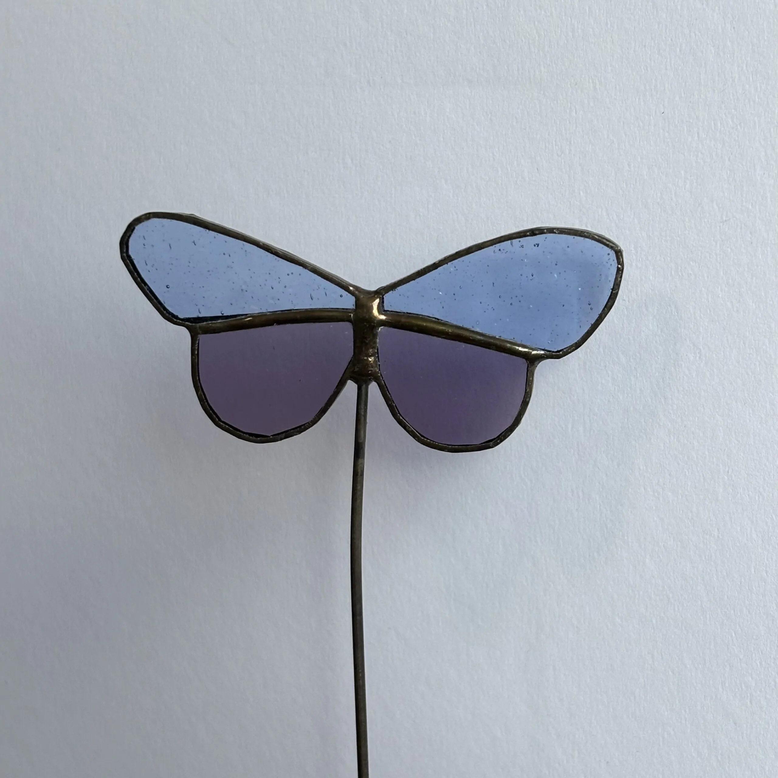 Tiffany glaskunst: een licht blauw met paarse vlinder op een steel.