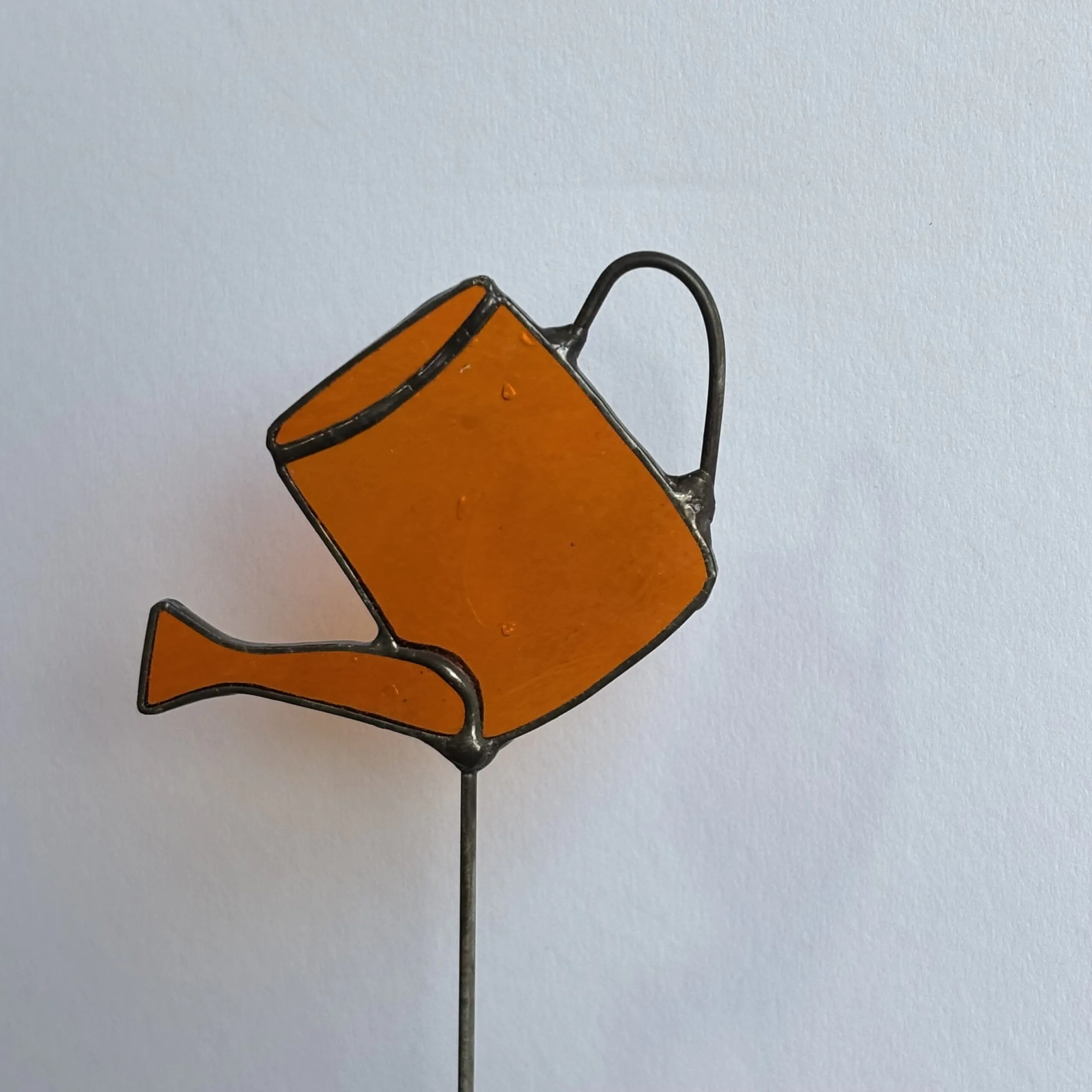 Tiffany glaskunst: een oranje gieter op een steel.