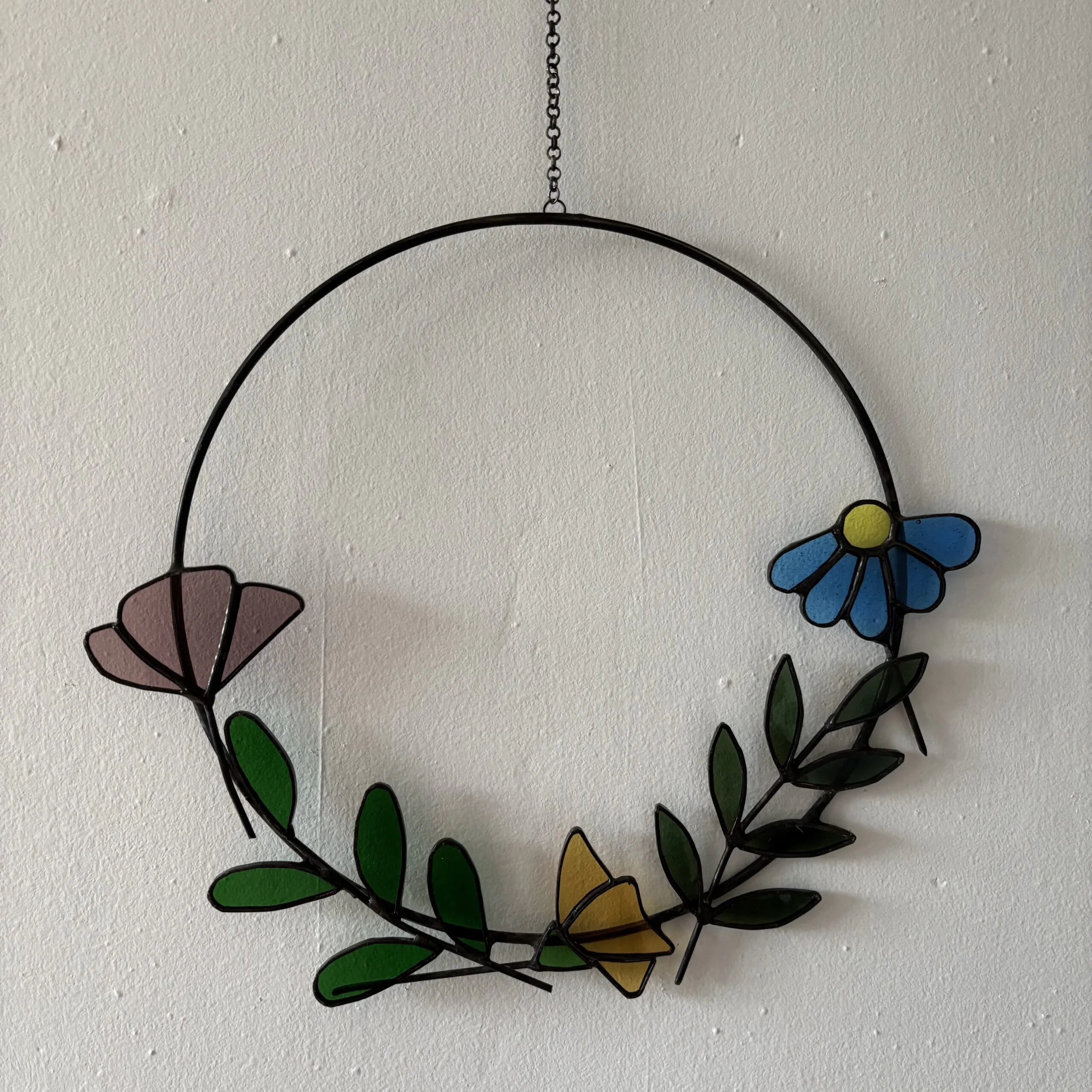 Glas in lood hanger: een metalen ring met daarin 3 soorten bloemen en 2 takjes.