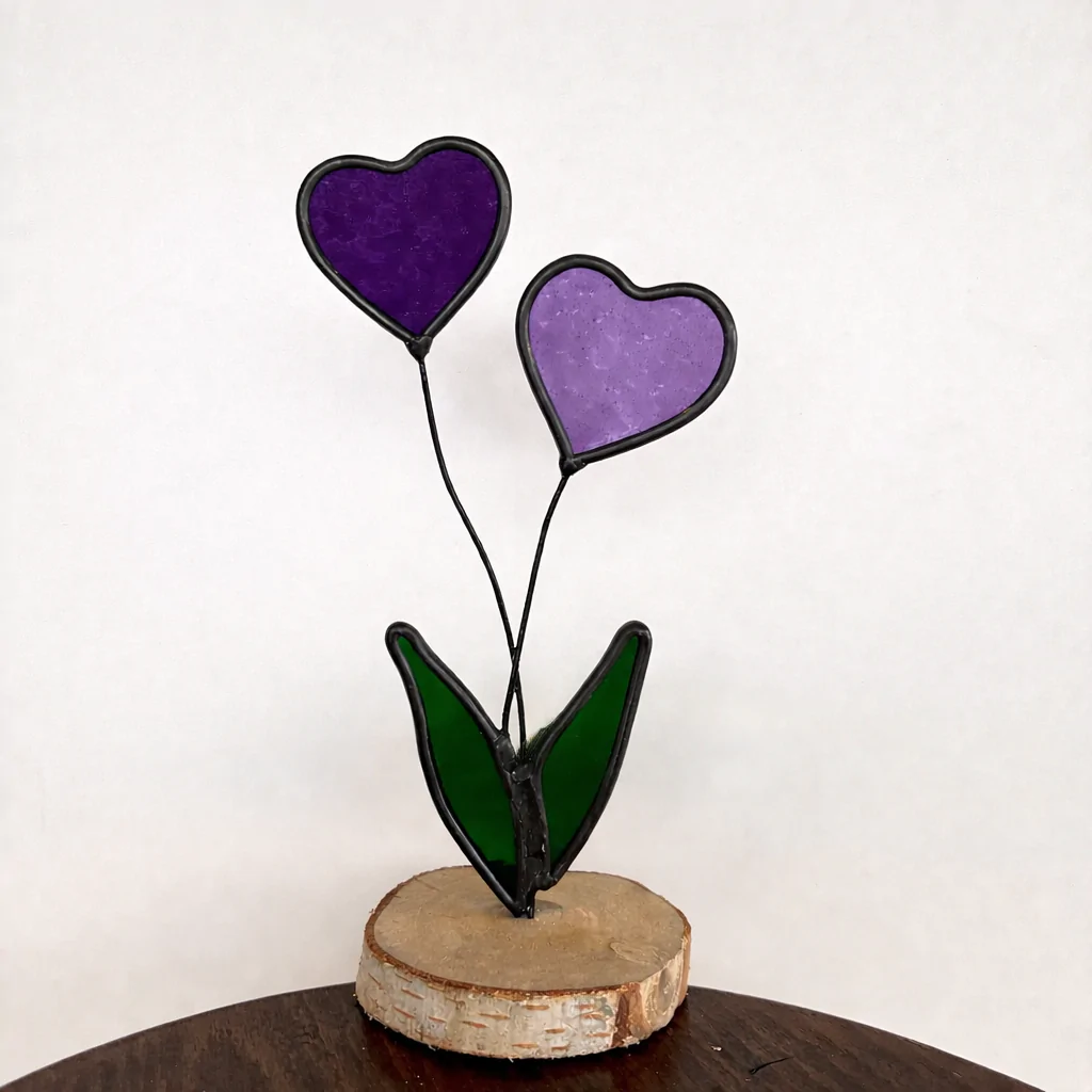 Glas in lood: 2 hartjes op steeltjes met onderaan 2 blaadjes, als geheel op een houten schijfje.