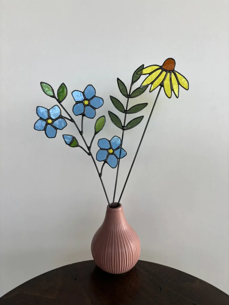 Tiffany glaskunst: sfeerfoto van een tak met 3 blauwe vergeet-mij-nietjes, 1 knop en 3 groene blaadjes. En een olijf groene 7-blad tak en een gele zonnehoed.